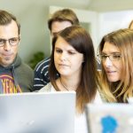 Kuusi henkilöä katsoo tietokoneen näyttöä hämmästellen
