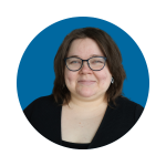 Kuvassa sinisellä taustalla hymyilevä nainen, jolla on sinertävät silmälasit, ruskeat lyhyet hiukset ja musta paita.