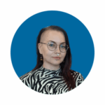 Sinisellä taustalla tummahiuksinen nainen, jolla on pyöreät silmälasit ja mustavalkokuvioinen paita.