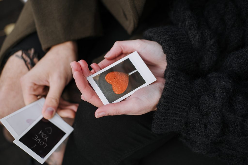 kaksi henkilöä katsoo polaroid kuvia, joissa kaikissa on kuvattu rakkautta ja välittämistä