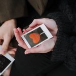 kaksi henkilöä katsoo polaroid kuvia, joissa kaikissa on kuvattu rakkautta ja välittämistä