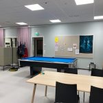 Riistaveden nuokkari. Kuvassa taka-alalla biljardipöytä ja etualalla pöytä ja tuoleja.