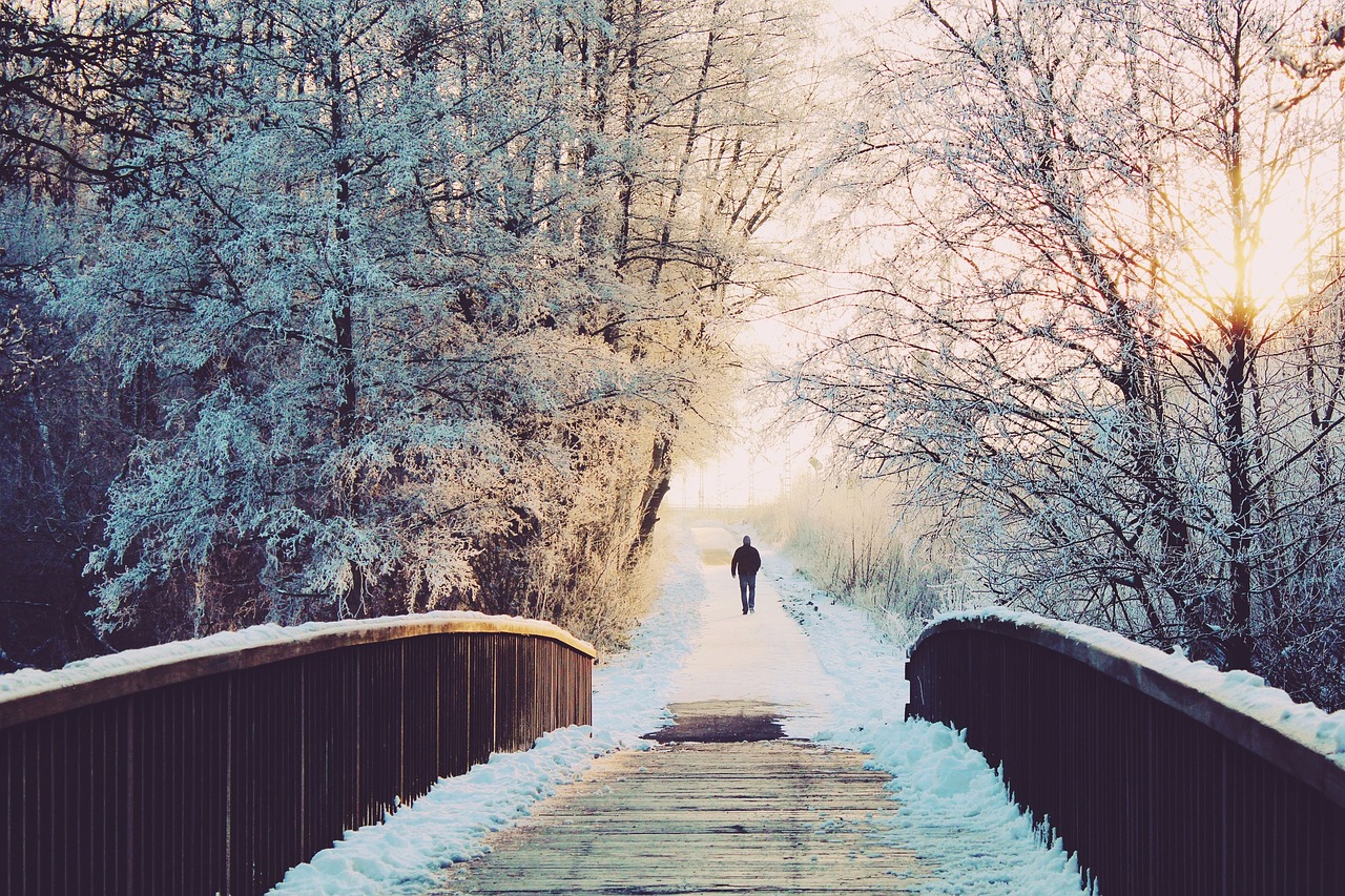 Talvinen maisema jossa silta, ja ihminen kävelee sillalta pois.