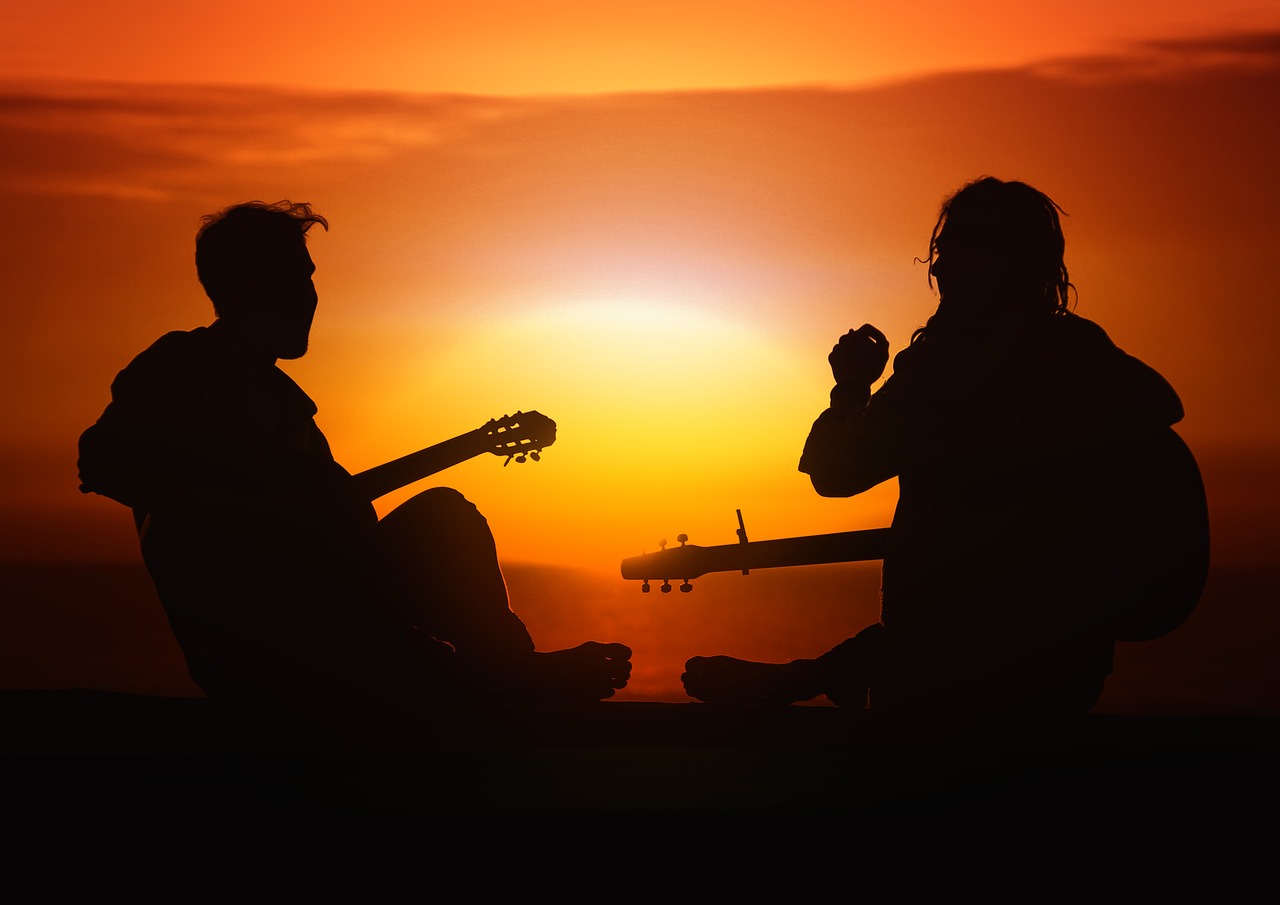 Auringonlaskussa ihmiset soittavat kitaraa.