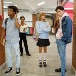 Joukko nuoria seisoo koulun käytävällä. Avainsanoja: koulu, opiskelu, kaveruus