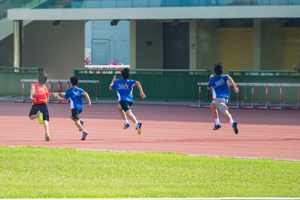 Nuoret juoksevat kilpaa urheilukentällä.