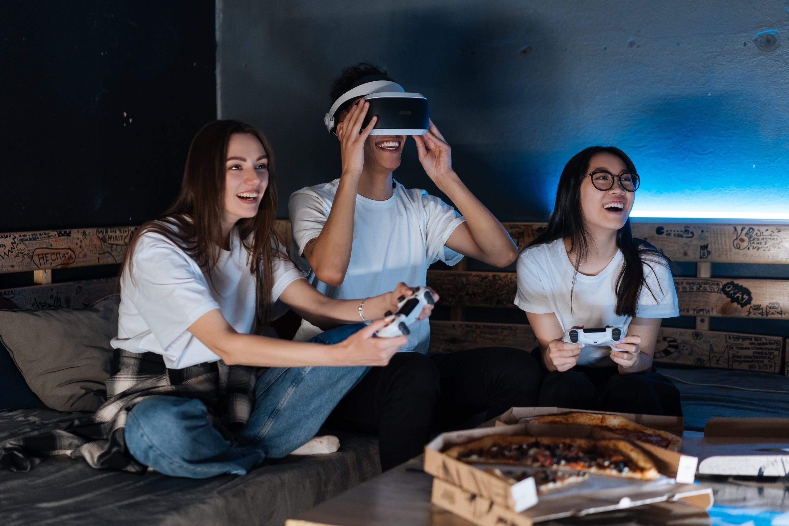 Nuoret istuvat sohvalla, pelaavat, käyttävät VR-laseja ja nauravat.