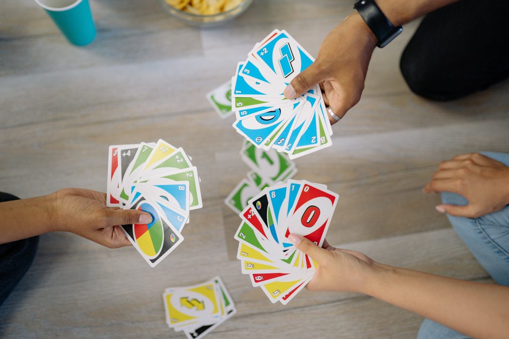 Lattialla ihmiset pelaavat Uno- korttipeliä.