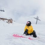 Nuori on lumilautailemassa ja on istahtanut maahan laskettelumäessä. Avainsanoja: talvi, loma, hiihtoloma, laskettelu, lumilautailu, retki, ilo, liikunta, ympäristö