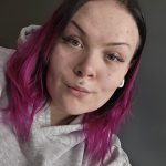 Nuorisonohjaaja Marianne Ihalainen. Nainen, jolla on hiuksissa ruskeaa ja pinkkiä väriä ja päällään harmaa huppari.