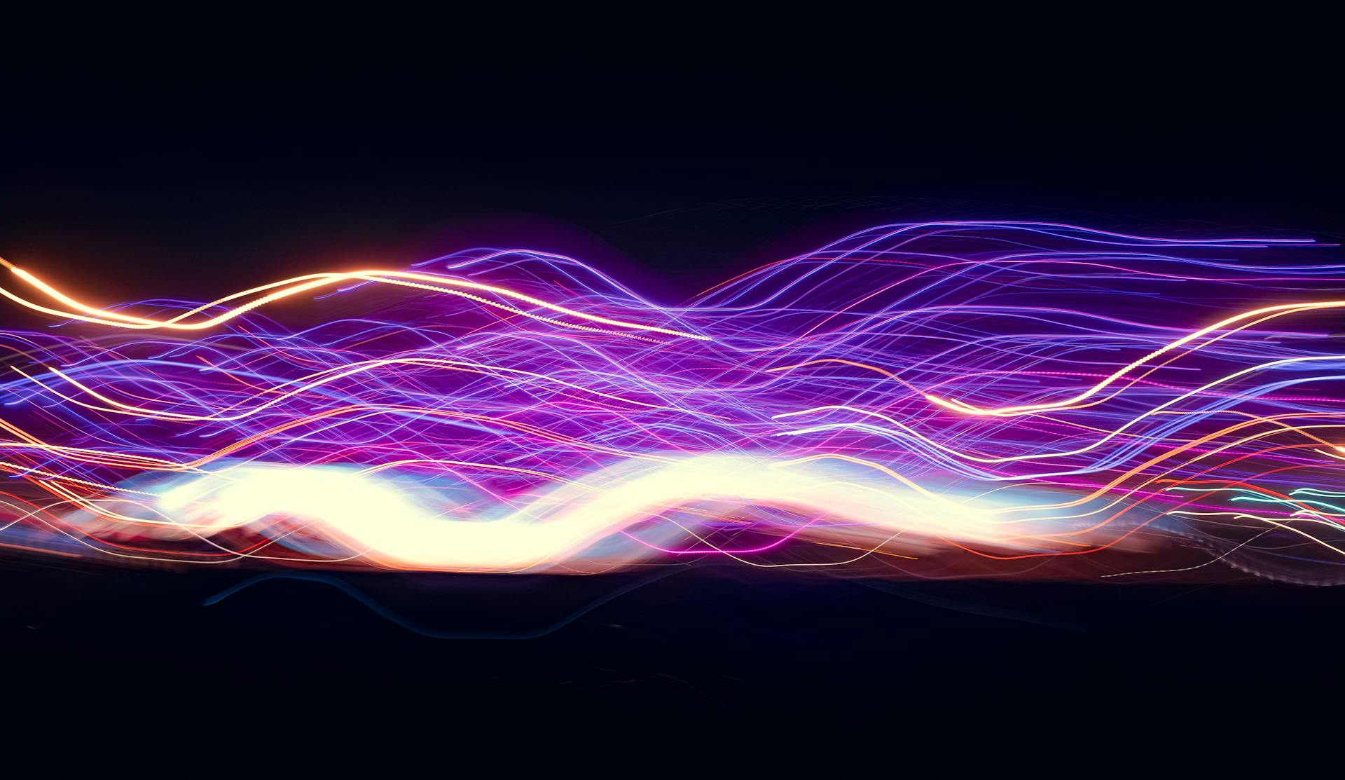 Aaltoileva valotaideteos mustaa taustaa vasten. Violetin ja kullan eri sävyisiä ohuita lankamaisia viivoja aaltoilee läpi kuvan vaakasuunnassa.