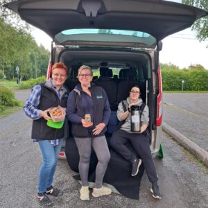 Pilvisenä päivänä Walkers -auton takana oleskelee kolme hymyilevää työntekijää, joista yksi pitelee kahvitermosta, toinen Fanta -tölkkiä ja kolmas eväsrasiaa, joka on täynnä kanelikorppuja.