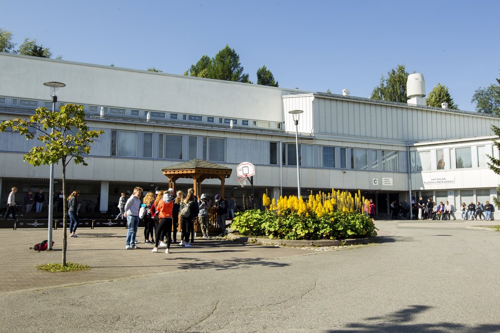 Hatsalan klassillinen koulu. Pihalla nuorisoa ja kukkaistutuksia.