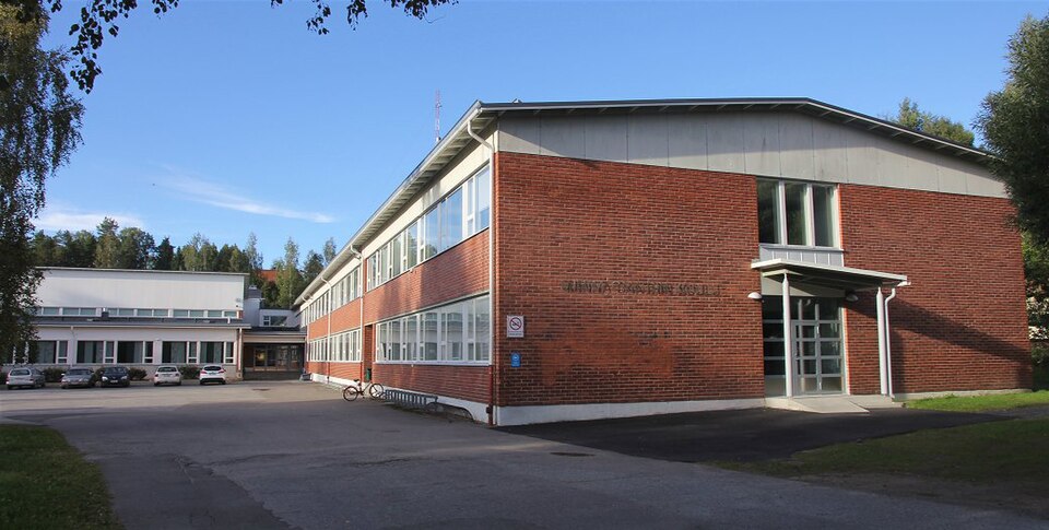 Minna Canthin koulu. Punatiilinen rakennus, jonka päädyssä Minna Canthin koulu -kyltti. Taempana vaalea lisäosa, jonka edessä autoja sisäpihalla.