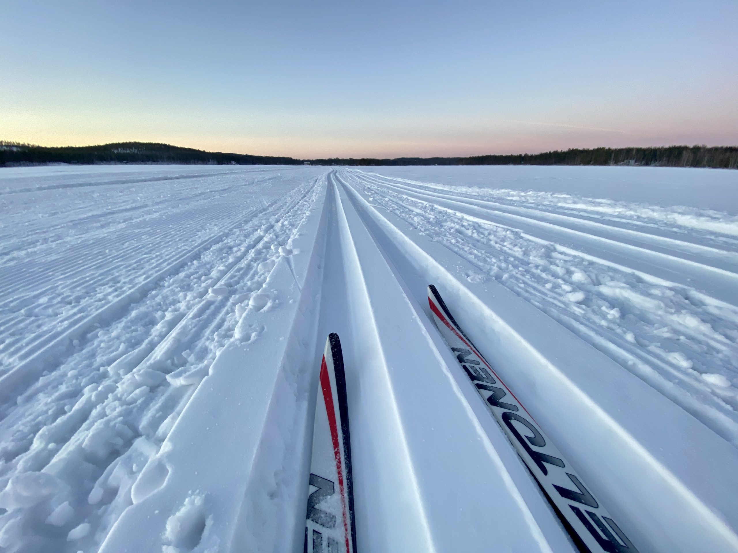 Talvinen maisema jäältä, jossa hiihtolatu ja suksen kärjet.