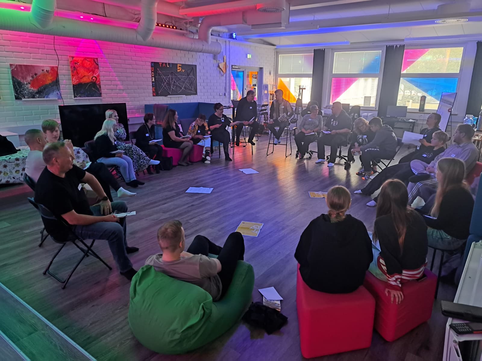 nuoria ja aikuisia istuu ympyrässä ja keskustelevat keskenään