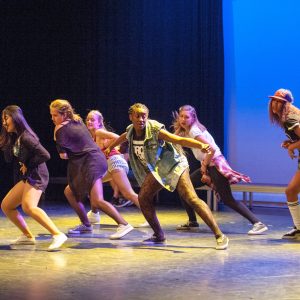 Ryhmä nuoria hiphop tanssijoita esiintymislavalla sisätilassa